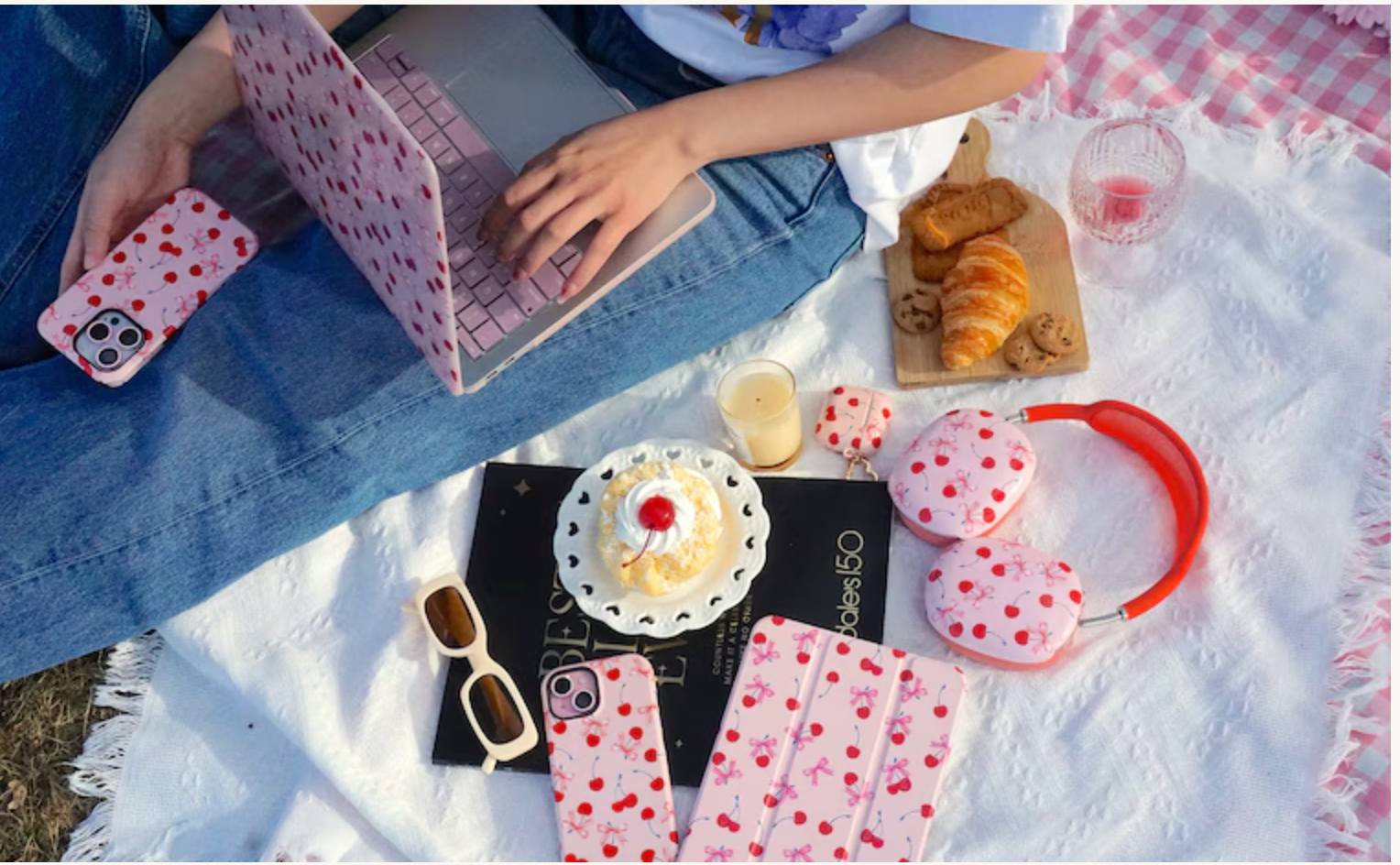 Matching cherry phone, tablet, laptop and earbud cases at a picnic